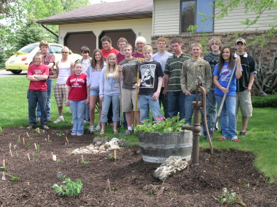 A group of people standing behind the rain garden they planted