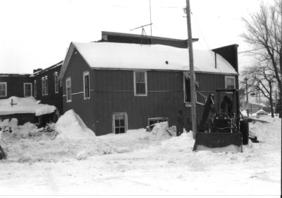A tractor next to an old building after snow storm